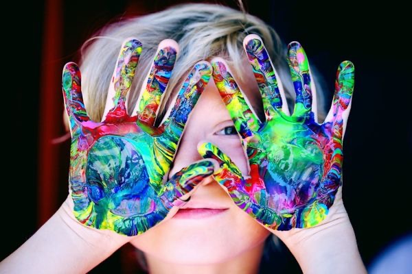 A child holding their hands up with paint on their hands